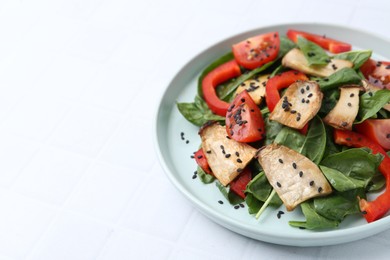 Photo of Tasty salad with eryngium mushrooms, vegetables, spinach and sesame on white tiled table, closeup. Space for text