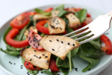 Photo of Eating tasty salad with eryngium mushrooms at table, closeup