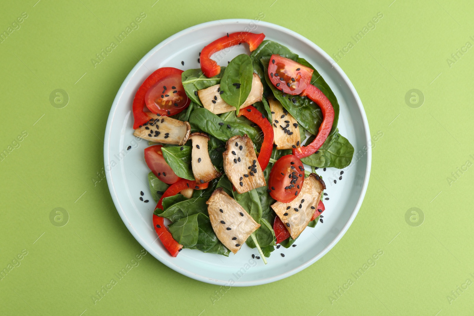 Tasty salad with eryngium mushrooms, vegetables, spinach and sesame on green background, top view Photo of Tasty salad with eryngium mushrooms, vegetables, spinach and sesame on green background, top view