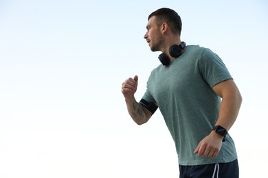 Photo of Athletic young man in sportswear running outdoors, low angle view. Space for text