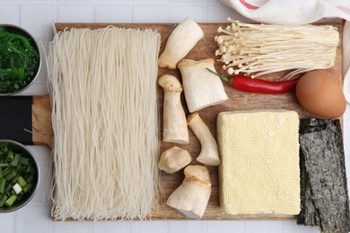 Photo of Enoki, king oyster (eryngii) mushrooms and other ingredients for ramen on white table, flat lay