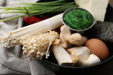 Photo of Enoki, king oyster (eryngii) mushrooms and other ingredients for ramen in bowl on table, closeup