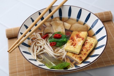 Photo of Tasty ramen with king oyster (eryngii) mushrooms in bowl on white table, closeup