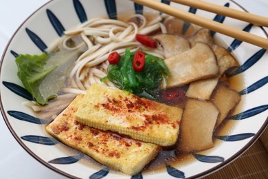 Photo of Tasty ramen with king oyster (eryngii) mushrooms in bowl on table, closeup