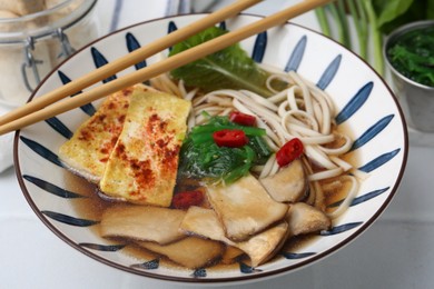 Photo of Tasty ramen with king oyster (eryngii) mushrooms in bowl on light table, closeup
