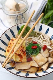 Photo of Tasty ramen with king oyster (eryngii) mushrooms in bowl on table, closeup