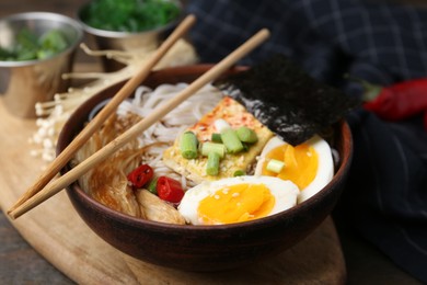 Photo of Tasty ramen with enoki mushrooms in bowl on table, closeup