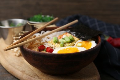 Photo of Tasty ramen with enoki mushrooms in bowl on table, closeup