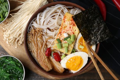 Photo of Tasty ramen with enoki mushrooms in bowl on table, flat lay