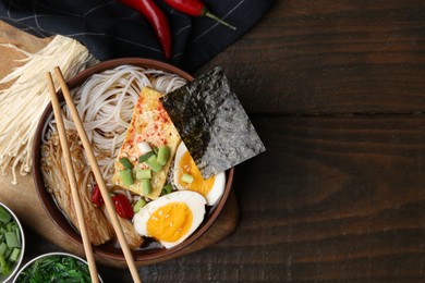 Photo of Tasty ramen with enoki mushrooms in bowl on wooden table, flat lay. Space for text