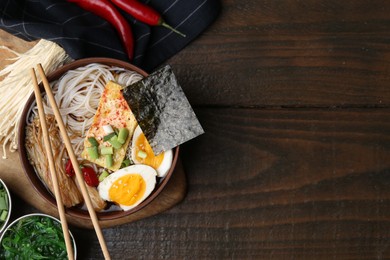 Photo of Tasty ramen with enoki mushrooms in bowl on wooden table, flat lay. Space for text