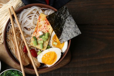 Photo of Tasty ramen with enoki mushrooms in bowl on wooden table, top view