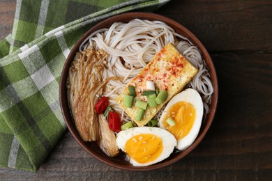 Photo of Tasty ramen with enoki mushrooms in bowl on wooden table, top view