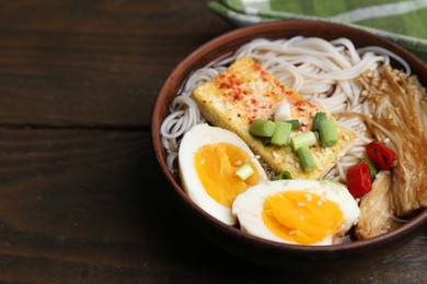 Photo of Tasty ramen with enoki mushrooms in bowl on wooden table, closeup