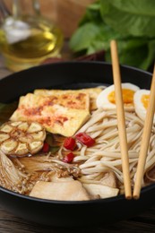 Photo of Tasty ramen with enoki and king oyster (eryngii) mushrooms in bowl on table, closeup