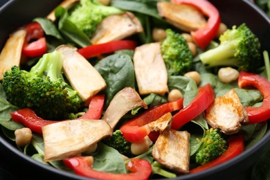 Photo of Tasty salad with eryngium mushrooms, chickpeas, vegetables and spinach in bowl, closeup
