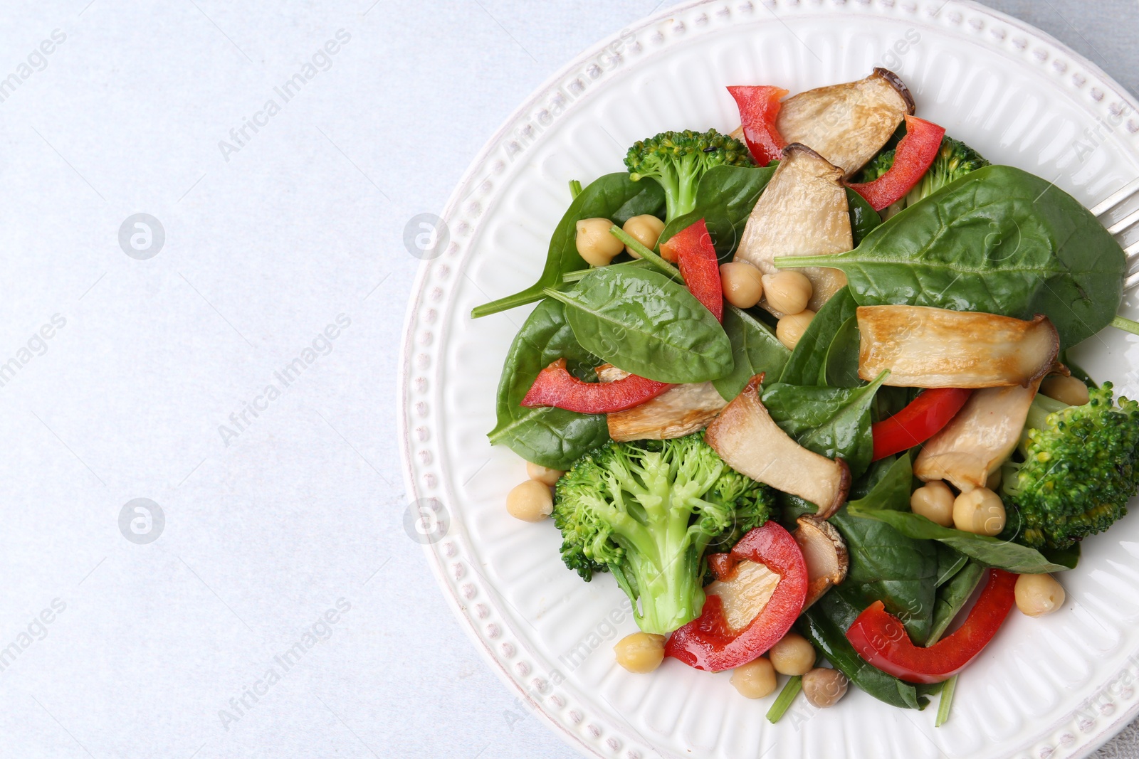 Tasty salad with eryngium mushrooms, chickpeas, vegetables and spinach on light table, top view. Space for text Photo of Tasty salad with eryngium mushrooms, chickpeas, vegetables and spinach on light table, top view. Space for text