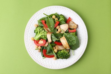 Photo of Tasty salad with eryngium mushrooms, chickpeas, vegetables and spinach on green background, top view