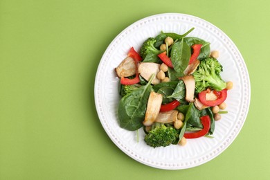 Photo of Tasty salad with eryngium mushrooms, chickpeas, vegetables and spinach on green background, top view. Space for text