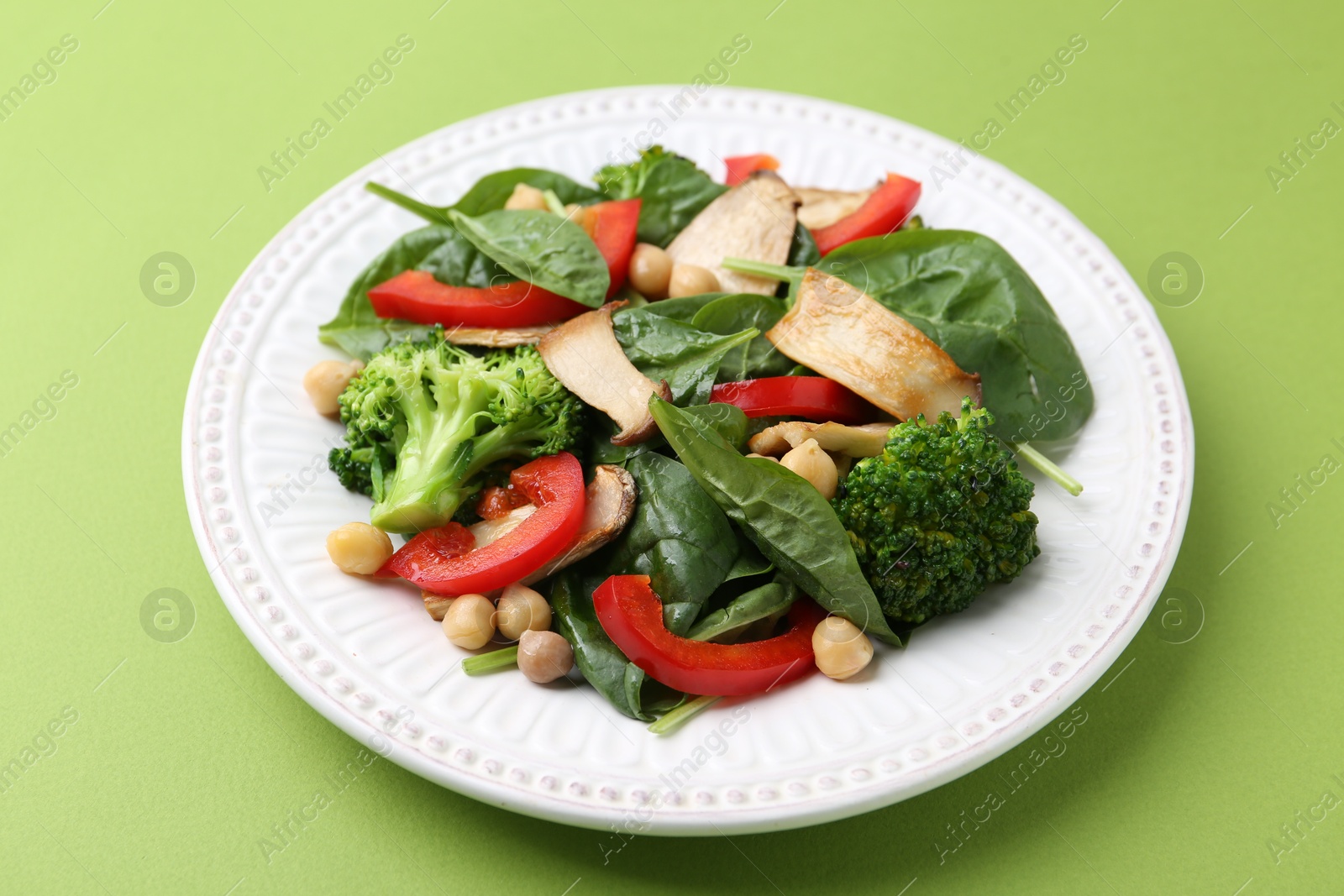 Tasty salad with eryngium mushrooms, chickpeas, vegetables and spinach on green background, closeup Photo of Tasty salad with eryngium mushrooms, chickpeas, vegetables and spinach on green background, closeup