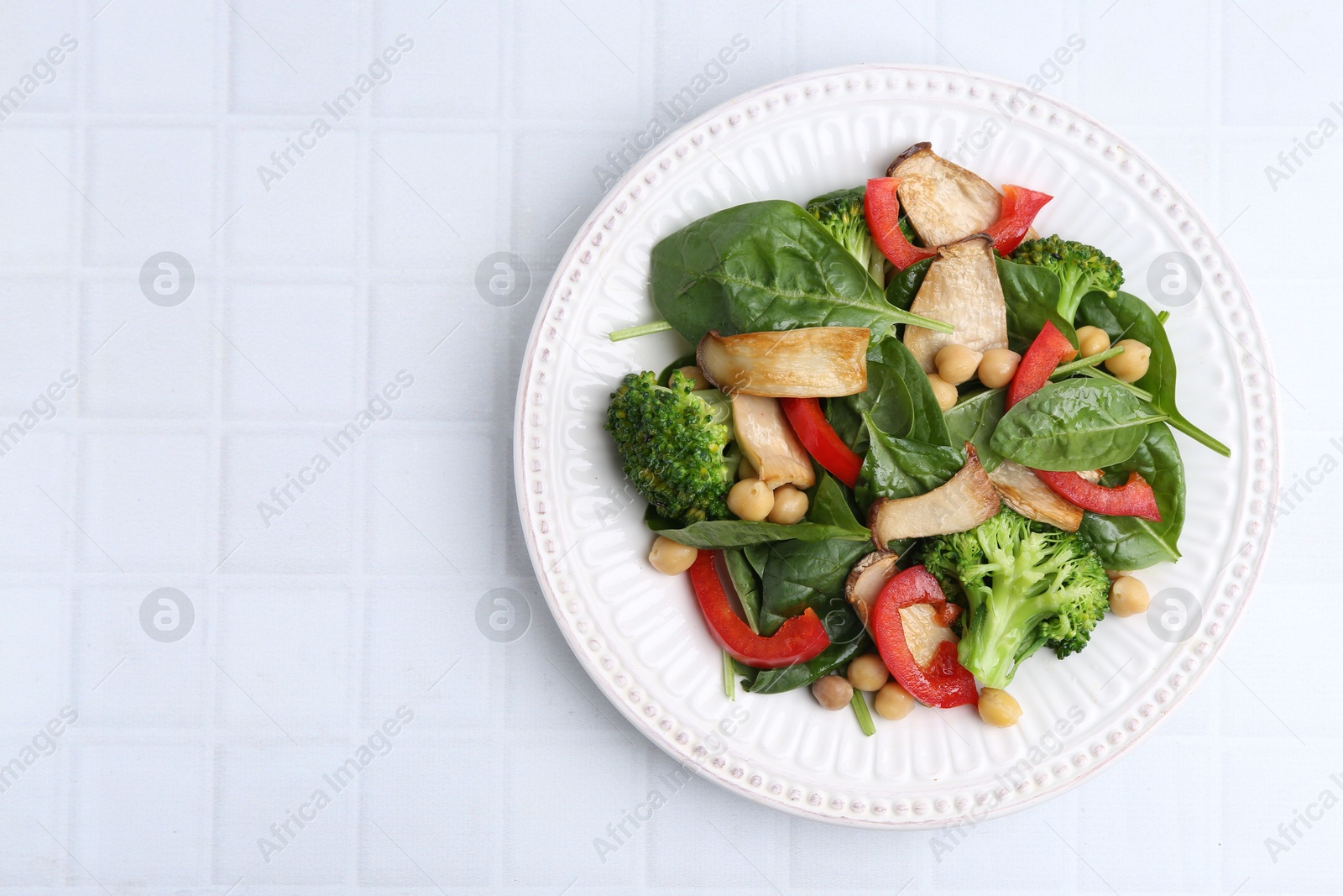 Tasty salad with eryngium mushrooms, chickpeas, vegetables and spinach on white tiled table, top view. Space for text Photo of Tasty salad with eryngium mushrooms, chickpeas, vegetables and spinach on white tiled table, top view. Space for text