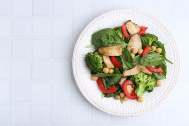 Photo of Tasty salad with eryngium mushrooms, chickpeas, vegetables and spinach on white tiled table, top view. Space for text