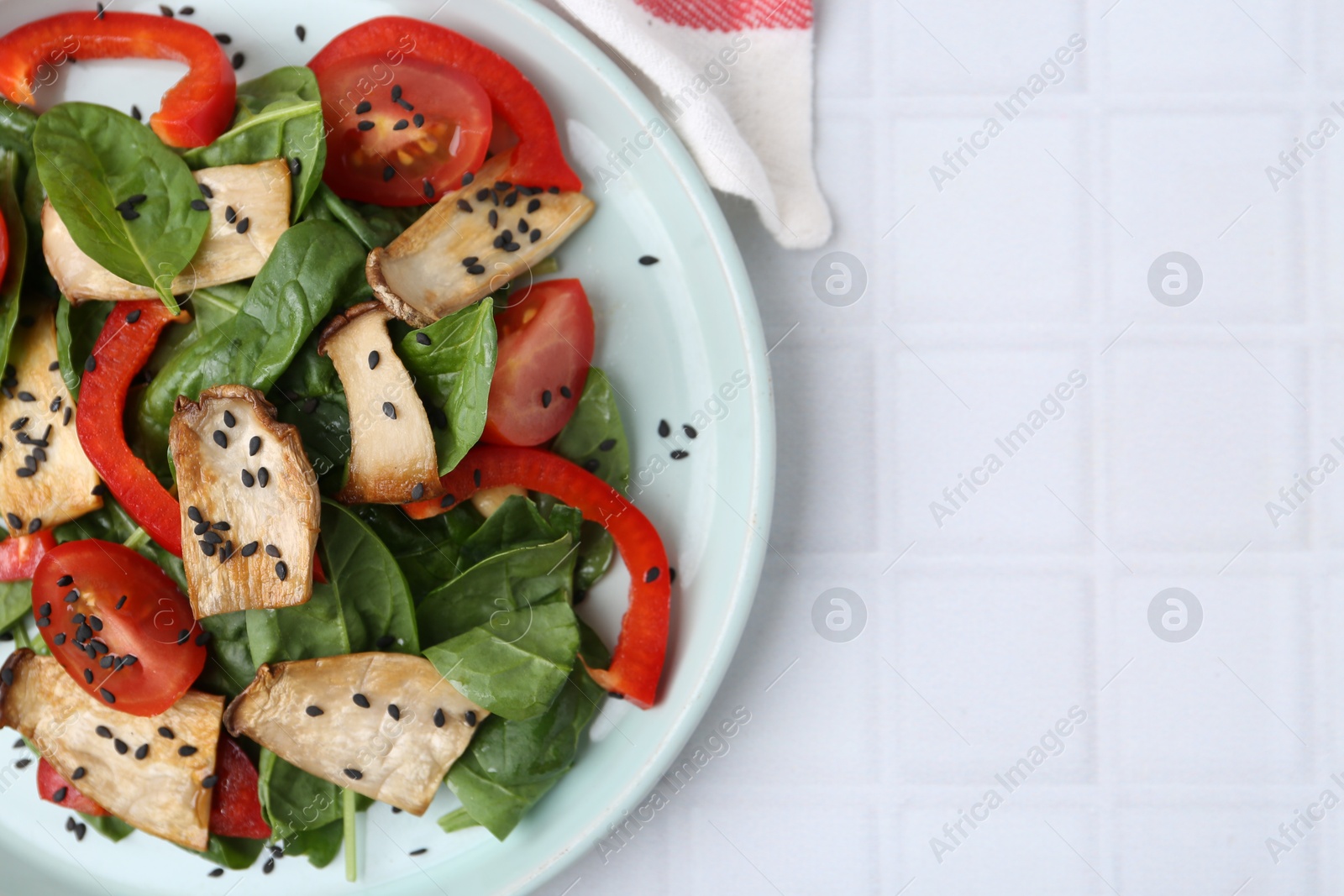 Tasty salad with eryngium mushrooms, vegetables, spinach and sesame on white tiled table, top view. Space for text Photo of Tasty salad with eryngium mushrooms, vegetables, spinach and sesame on white tiled table, top view. Space for text