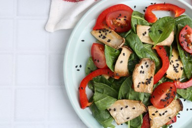 Photo of Tasty salad with eryngium mushrooms, vegetables, spinach and sesame on white tiled table, top view. Space for text