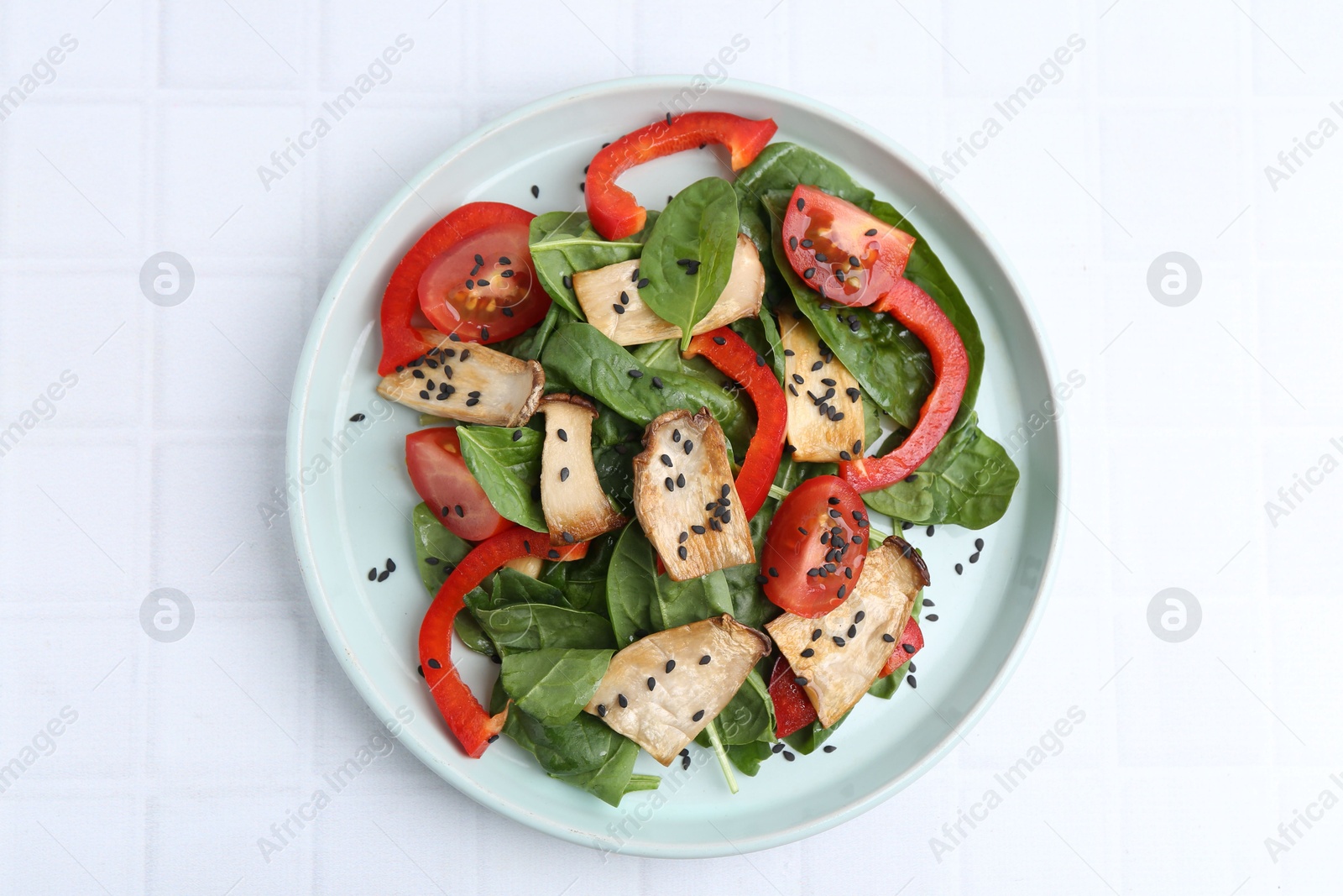 Tasty salad with eryngium mushrooms, vegetables, spinach and sesame on white tiled table, top view Photo of Tasty salad with eryngium mushrooms, vegetables, spinach and sesame on white tiled table, top view