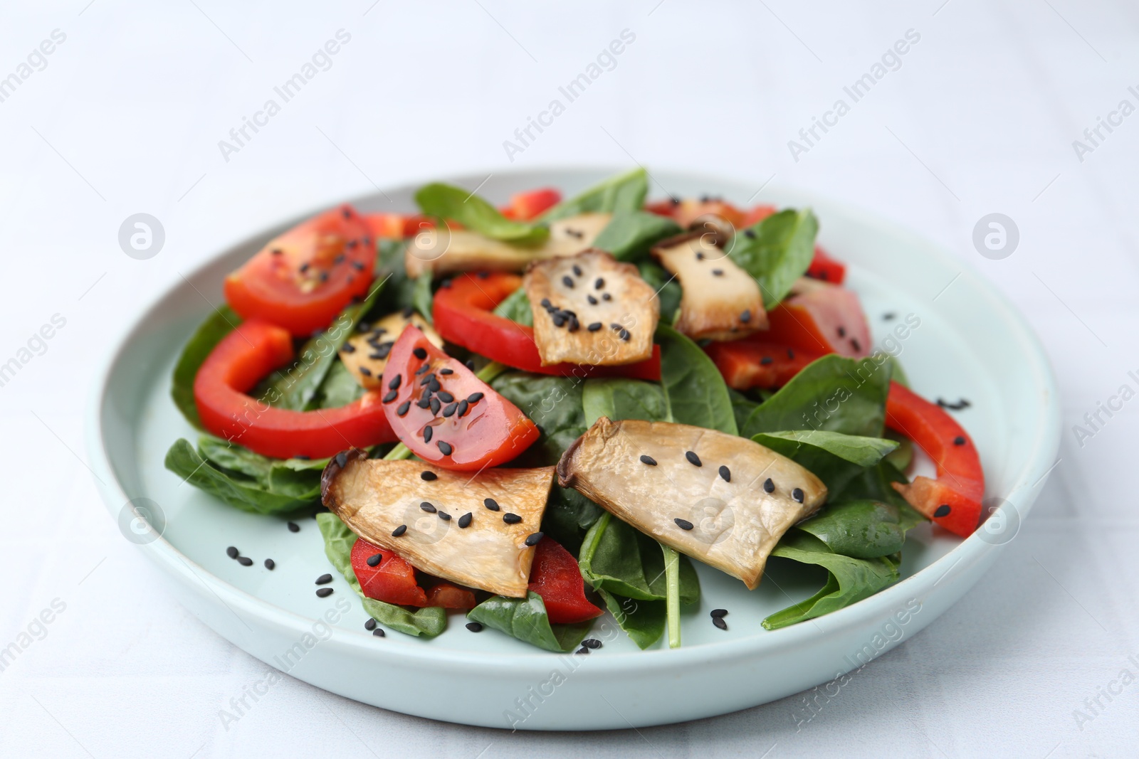 Tasty salad with eryngium mushrooms, vegetables, spinach and sesame on white table, closeup Photo of Tasty salad with eryngium mushrooms, vegetables, spinach and sesame on white table, closeup