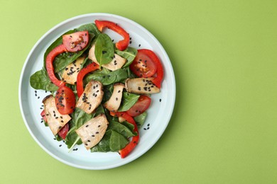 Photo of Tasty salad with eryngium mushrooms, vegetables, spinach and sesame on green background, top view. Space for text