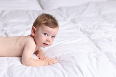 Photo of Cute little baby lying on bed indoors, space for text