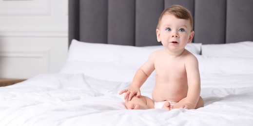Photo of Cute little baby on bed at home, space for text