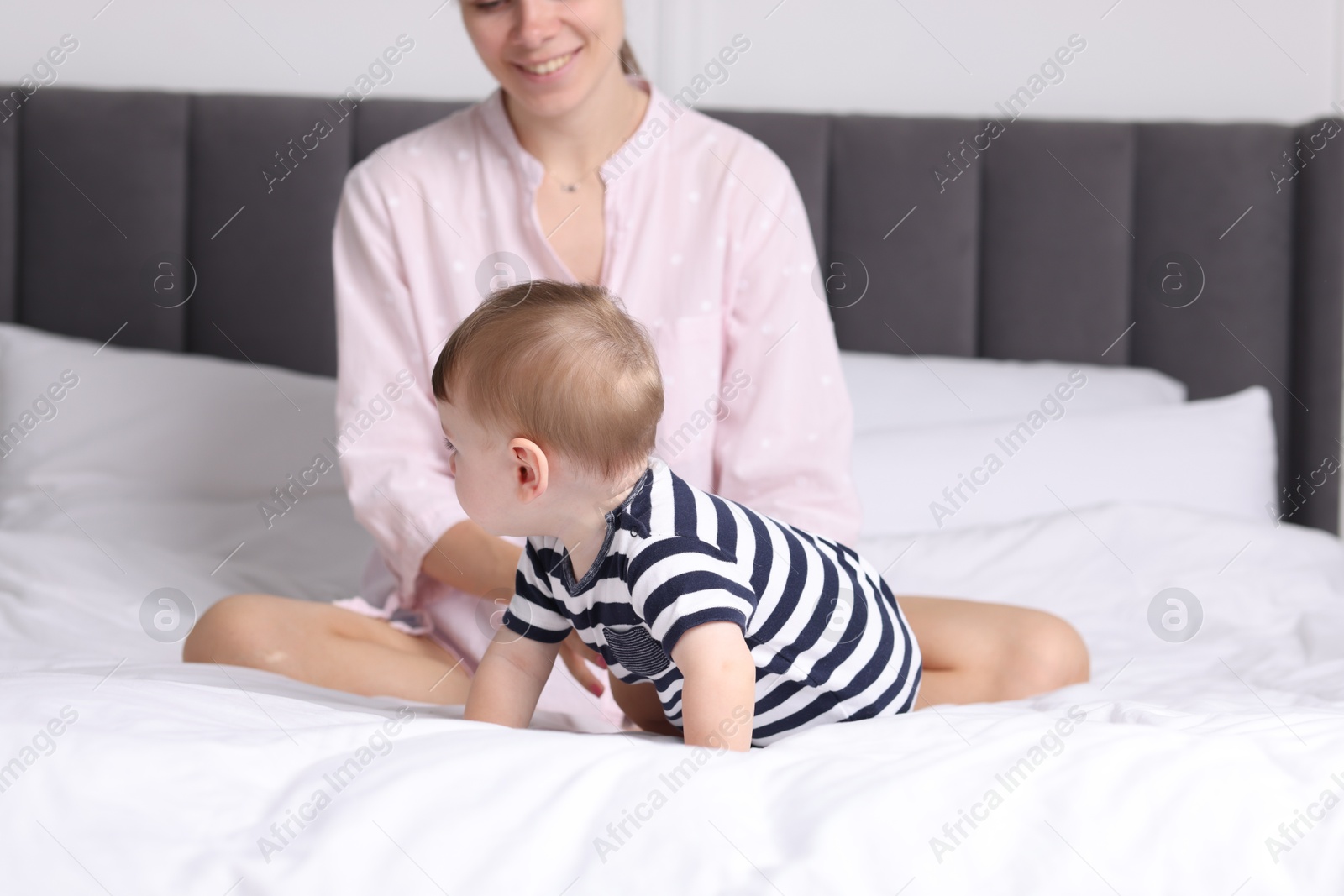 Photo of Mother with her cute little baby on bed at home, closeup