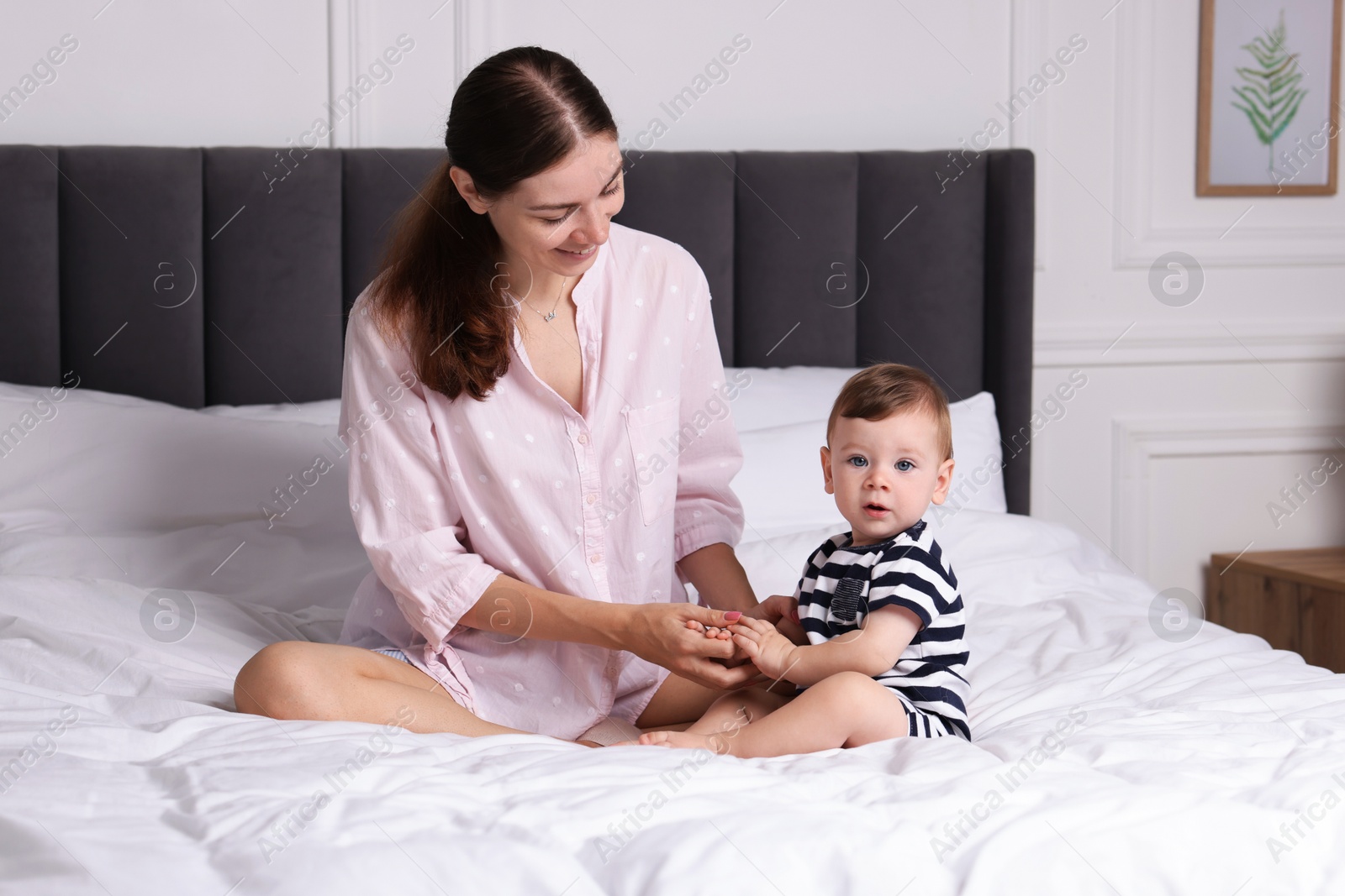 Photo of Mother with her cute little baby on bed at home