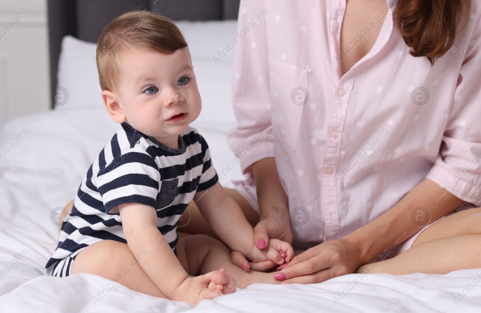 Photo of Mother with her cute little baby on bed at home, closeup