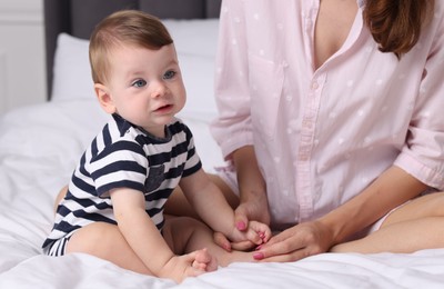 Photo of Mother with her cute little baby on bed at home, closeup