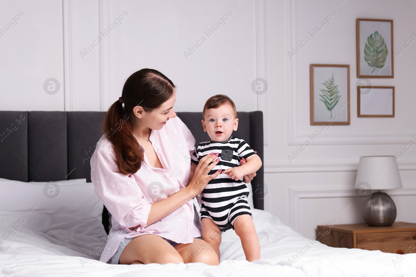 Photo of Mother with her cute little baby on bed at home