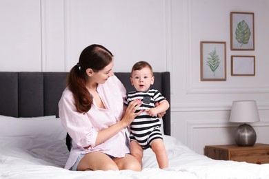 Photo of Mother with her cute little baby on bed at home