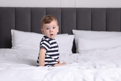 Photo of Cute little baby on bed at home, space for text