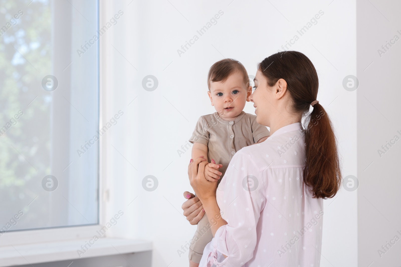 Photo of Mother with her cute little baby at home, space for text