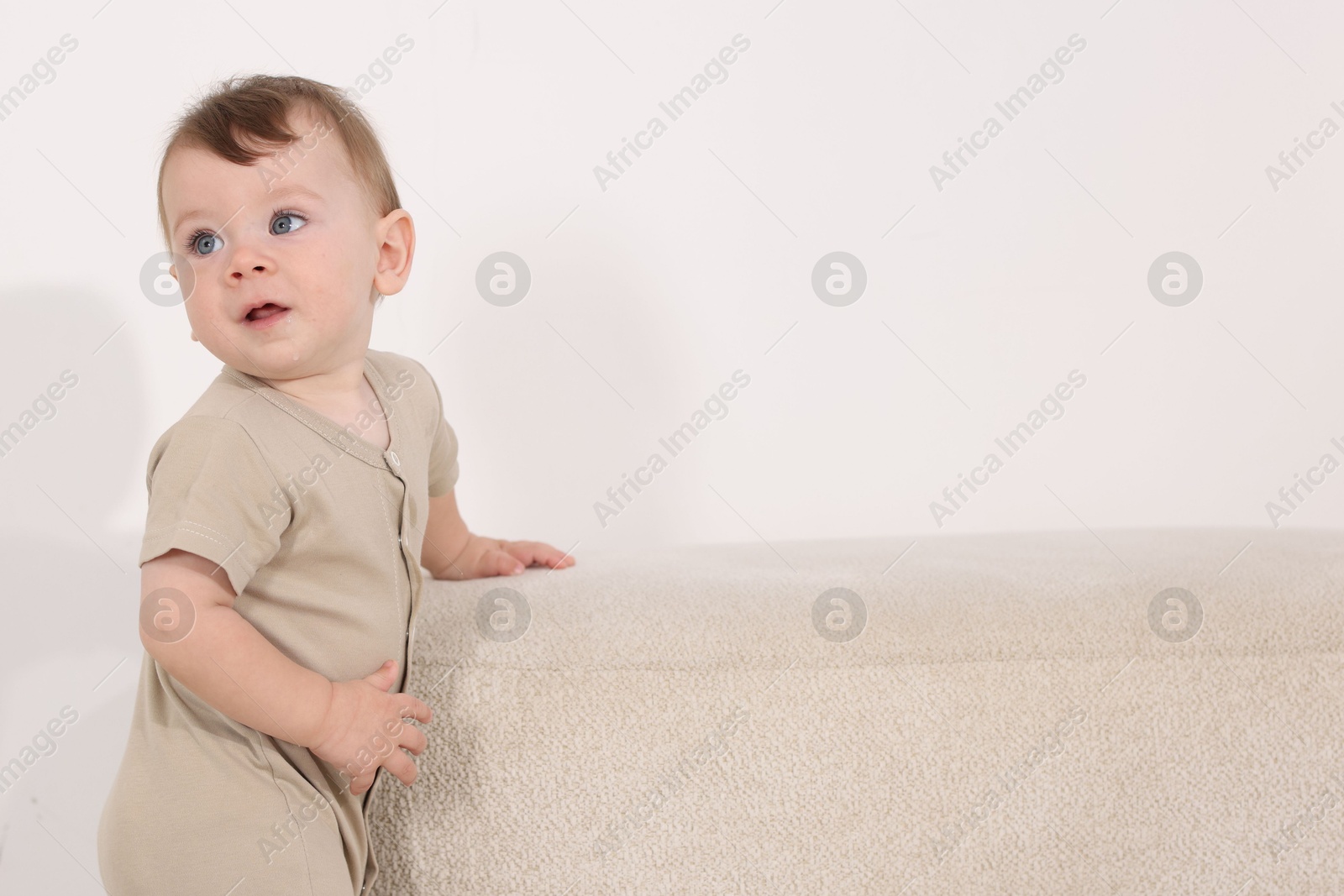 Photo of Cute little baby near pouf at home