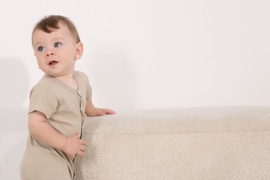 Photo of Cute little baby near pouf at home