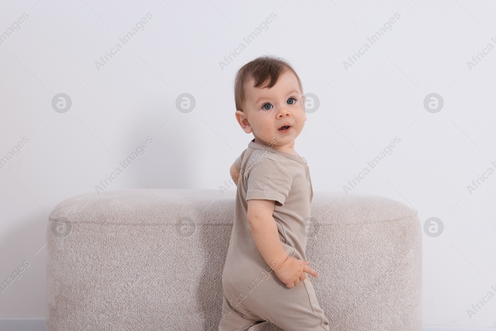 Photo of Cute little baby near pouf at home