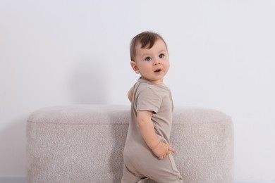 Photo of Cute little baby near pouf at home