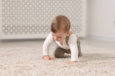 Photo of Cute little baby with toy on floor at home