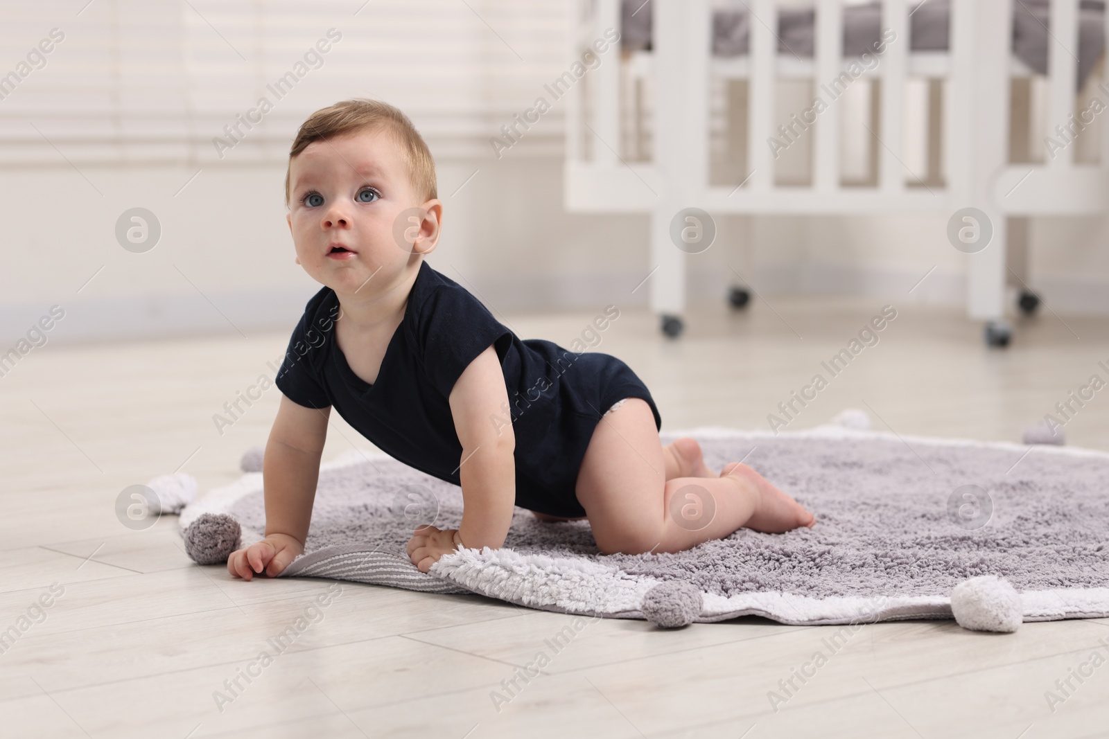 Photo of Cute little baby crawling on floor at home, space for text