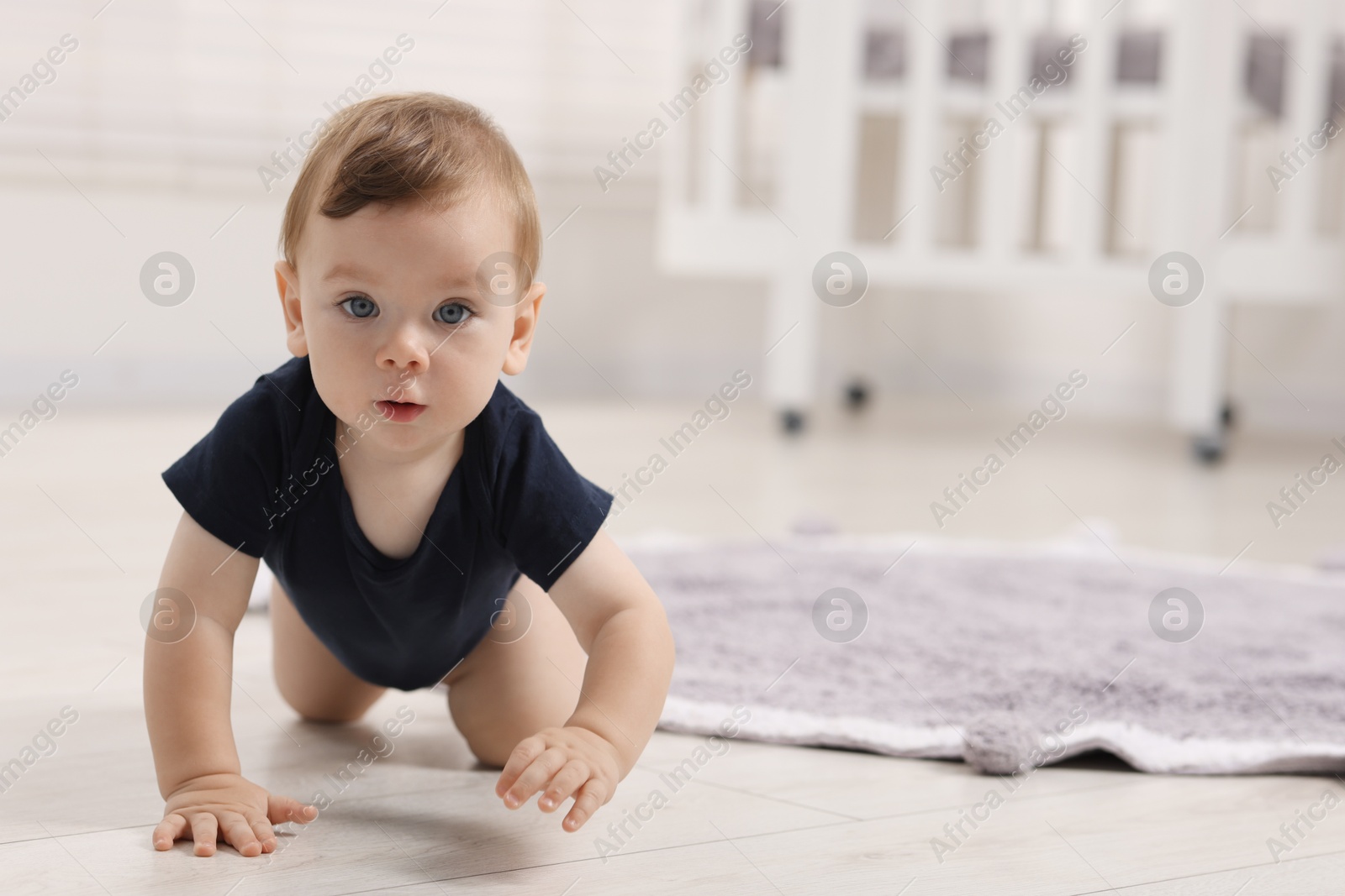 Photo of Cute little baby crawling on floor at home, space for text