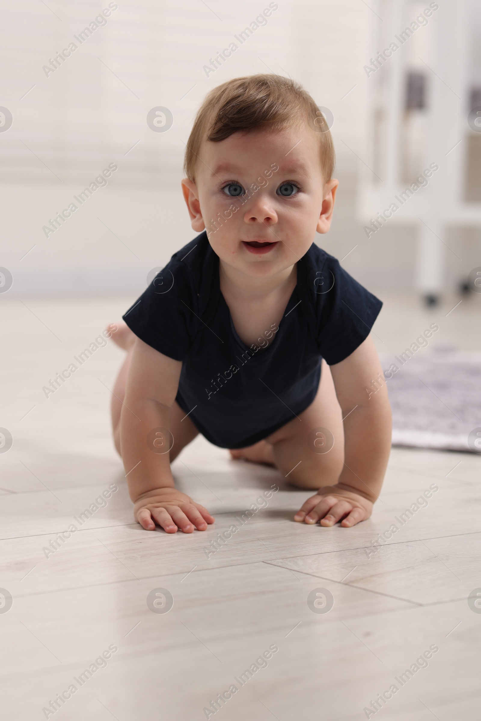 Photo of Cute little baby crawling on floor at home