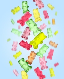 Image of Sweet jelly candies in shape of bear falling against light blue background